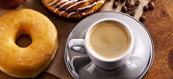 Breakfast table with coffee and a donut.