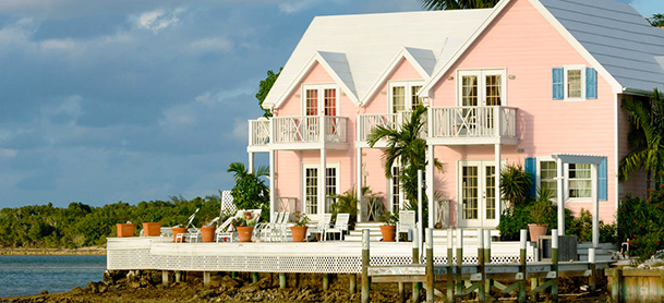 A pink waterfront house with a white deck