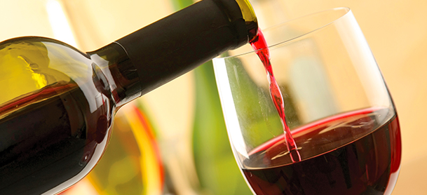 A bottle of red wine pouring into a glass