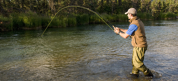 A man stands in ankle-deep water while fishing
