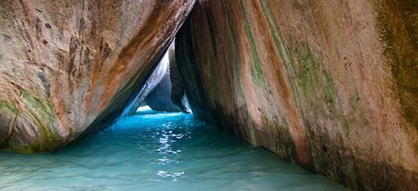 Two large rocks lean together in shallow water, forming a pathway