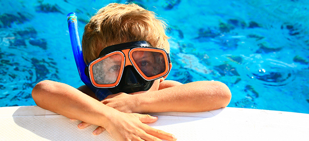 Kid in snorkle and mask relaxing half out of the water