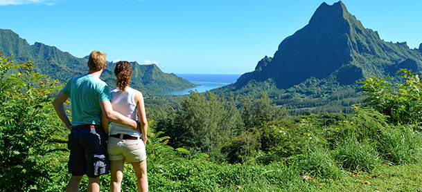 Man with arm around woman as they view green mountain