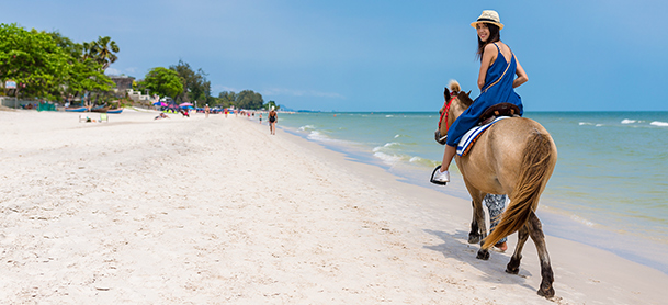 Woman riding horse on beach
