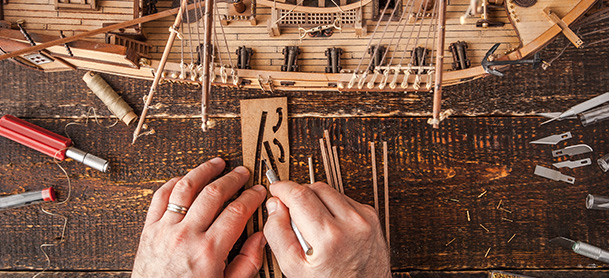 close up of hands working on boat model