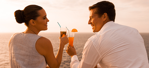 Couple dressed in white toasting a drink nearing sunset