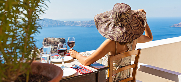 Woman in hat enjoying glass of wine overlooking water