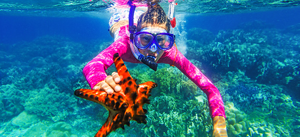 Woman snorkeling holding starfish
