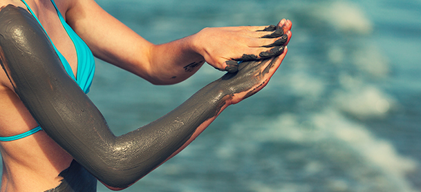 Woman covering her arm with a mud bath