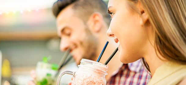 Man and woman enjoying cold drink in a jar using straws