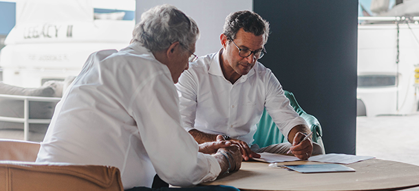 Two men discussing paperwork at a table