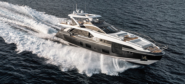An Azimut yacht speeds across the open sea, creating a dynamic water spray.