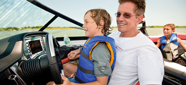Boy on dad's lap steering yacht