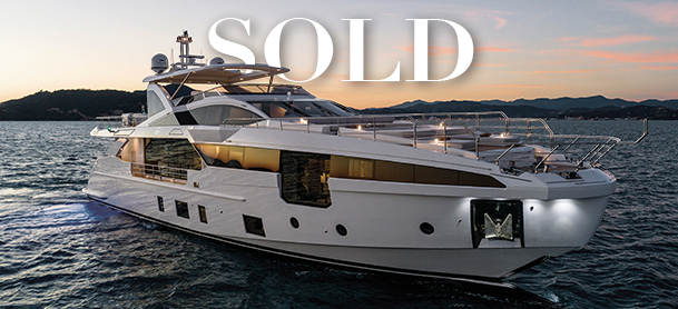 Luxurious white yacht on calm waters at sunset with mountains in the background, overlaid with the word "SOLD" in bold white letters, conveying elegance.