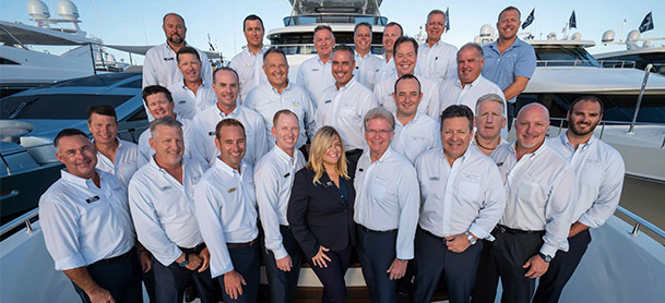 group of yacht team professionals in uniform standing on bow