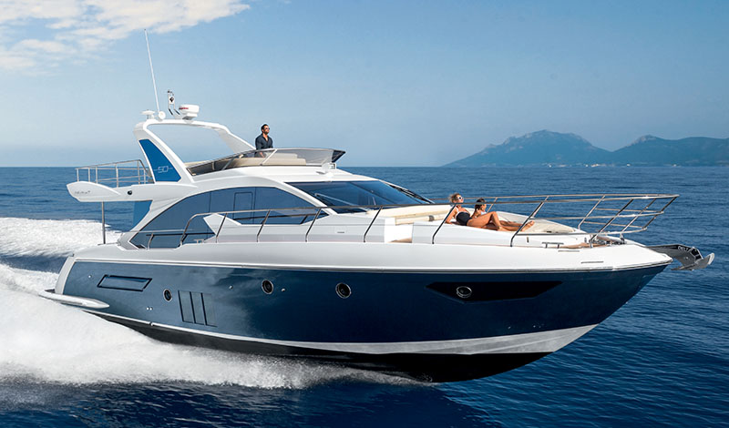 an azimut 50 flybridge cruising through open water with a women laying on the sunbed on the bow