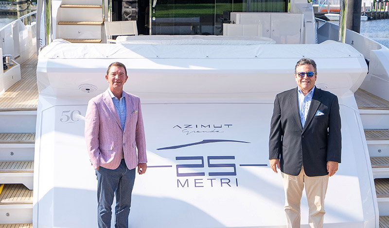 two yacht salesmen standing on a dock in front of an azimut grande 25 metri