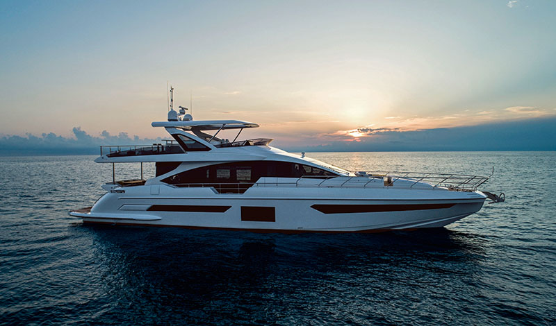 a profile view of an azimut grande 25 metri in open water as the sun sets behind it