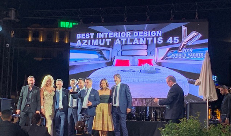 a group of people accepting an award at a yacht awards show with a photo of an azimut a45 in the background