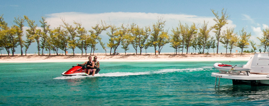 people riding jet ski by shore lined with trees