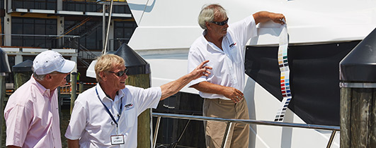 three men looking at colors samples against an ocean alexander yacht