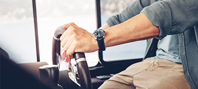 hands of man holding a steering wheel on a boat