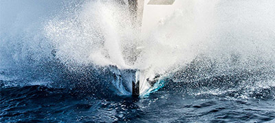 bow of a yacht breaking the water surface tension