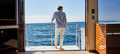 man standing on side deck of yacht looking out to open ocean