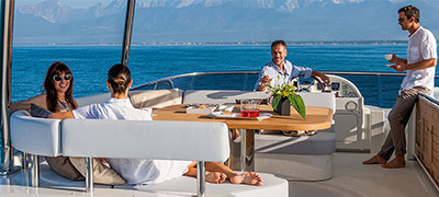 group of people relaxing, eating, and drinking on deck of a yacht