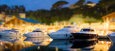 several yachts lined up along dock with lights on at sunset