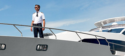 uniformed man standing on the bow of a yacht