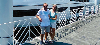 Couple smiling standing on dock in front of boats