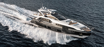 An Azimut yacht speeds across the open sea, creating a dynamic water spray.