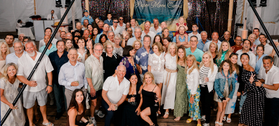 Group of people at an event under a tent, smiling and posing together.