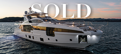 Luxurious white yacht on calm waters at sunset with mountains in the background, overlaid with the word "SOLD" in bold white letters, conveying elegance.