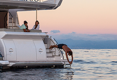 man diving off the swim platform of a yacht at sunset