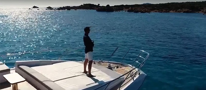 Man standing on the bow of a large yacht looking out to the open water