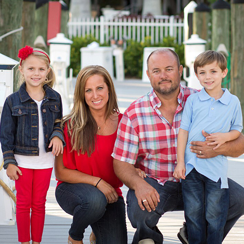 a couple stand with a young boy and young girl