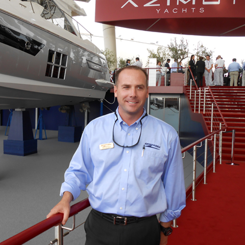 a man stands in front of a railing with an azimut yacht behind him