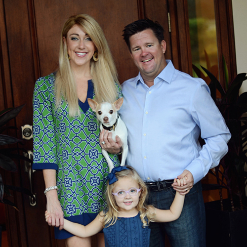 a couple stand smiling with a young girl in between them