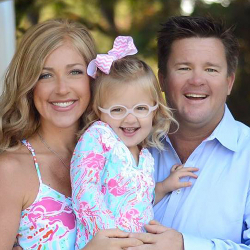 a couple hold a young girl while all three smile