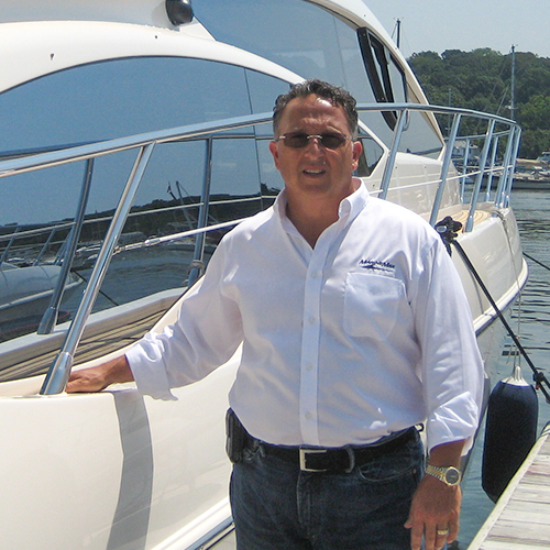 a man stands on a dock while resting a hand on a boat