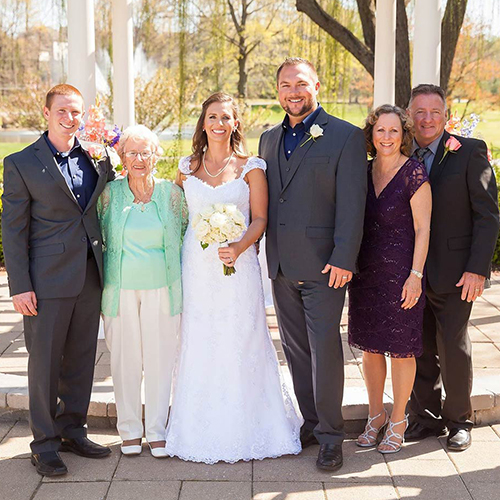 a couple stand at their wedding with family surrounding them