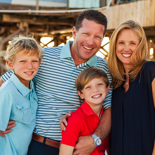 a couple smile with two young sons
